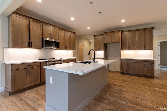 kitchen with light hardwood / wood-style floors, sink, stainless steel appliances, and decorative backsplash