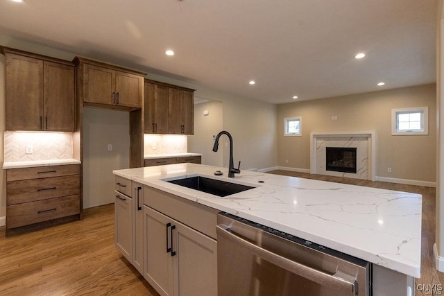 kitchen with dishwasher, light hardwood / wood-style floors, tasteful backsplash, sink, and a high end fireplace