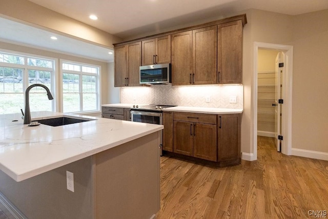 kitchen featuring sink, light hardwood / wood-style flooring, decorative backsplash, and light stone counters