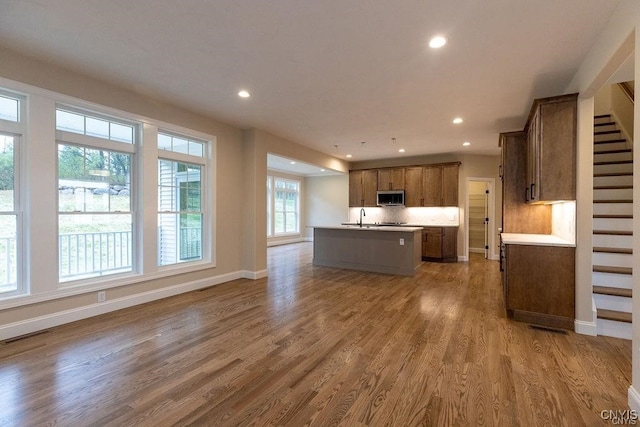 kitchen featuring hardwood / wood-style floors, sink, decorative backsplash, and an island with sink