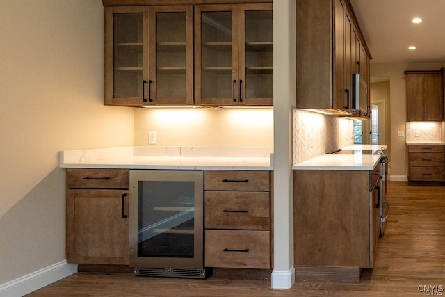 bar featuring dark wood-type flooring, wine cooler, stove, and tasteful backsplash