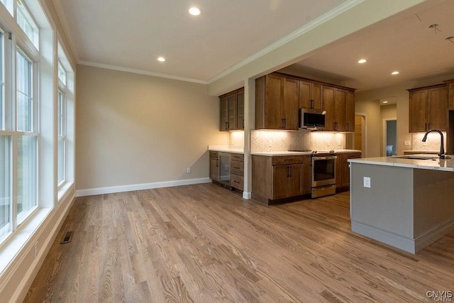 kitchen with backsplash, plenty of natural light, range, and light wood-type flooring