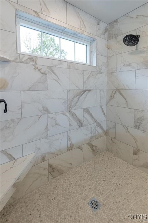 bathroom with tiled shower and a healthy amount of sunlight