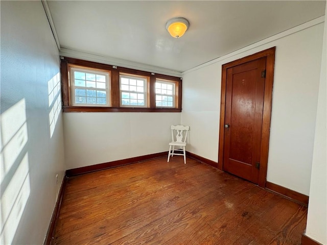 spare room with baseboards and dark wood-style flooring