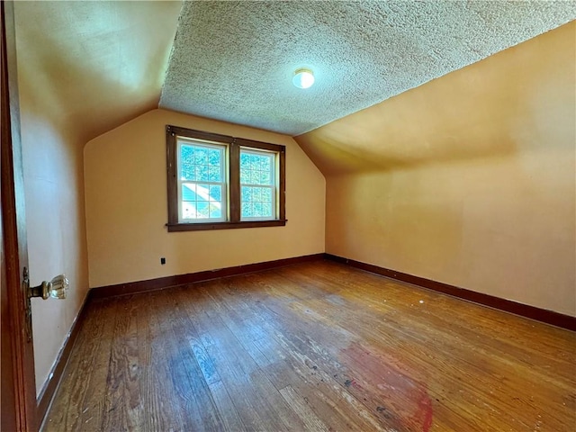 bonus room with a textured ceiling, baseboards, wood finished floors, and lofted ceiling