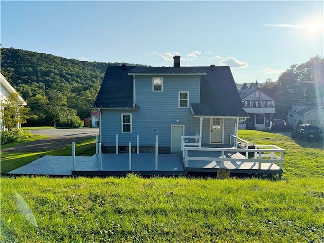 back of property featuring a deck and a yard