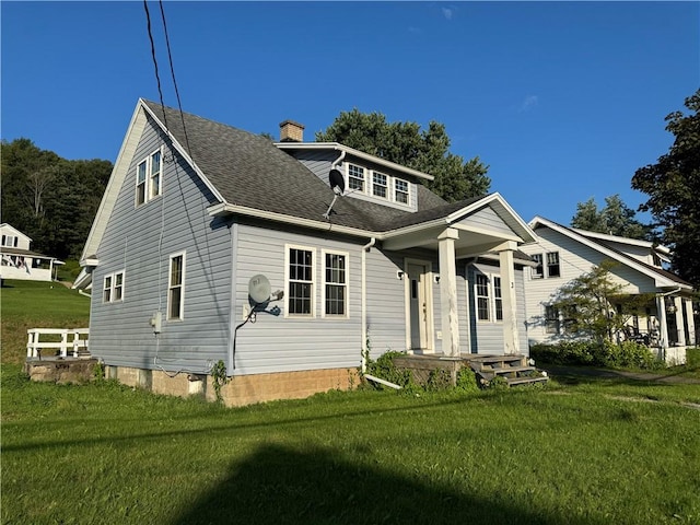 view of front of property featuring a front lawn, a chimney, and a shingled roof