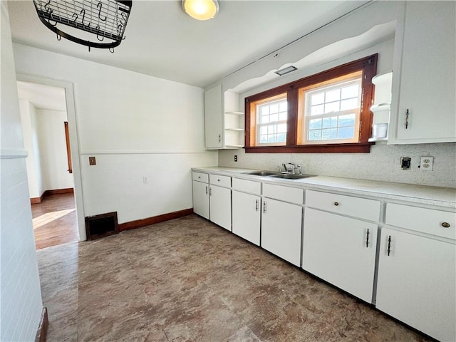 kitchen with light countertops, white cabinets, a sink, and open shelves