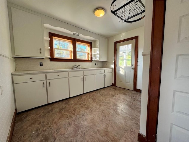 kitchen with white cabinets, light countertops, a sink, and open shelves