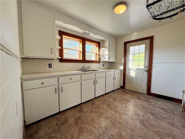 kitchen featuring wainscoting, light countertops, white cabinetry, open shelves, and a sink