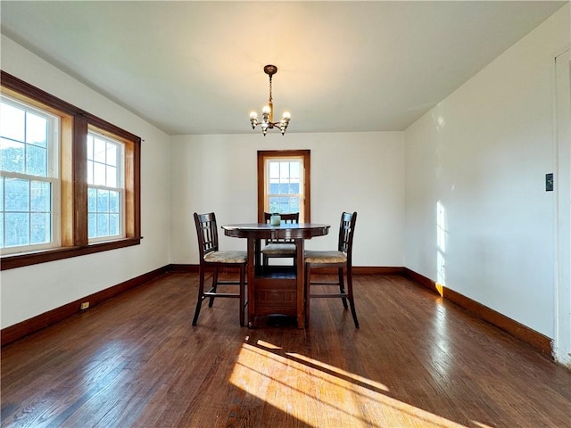 dining area featuring a chandelier, dark wood-style flooring, and baseboards