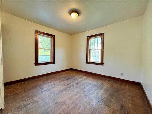 empty room featuring dark wood-style flooring and baseboards