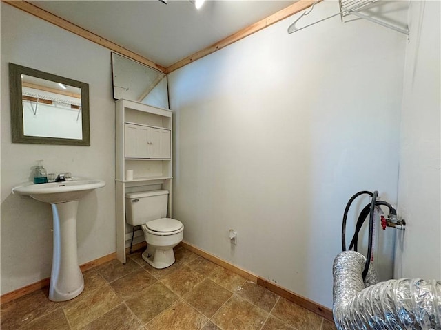 bathroom featuring toilet, stone finish flooring, and baseboards