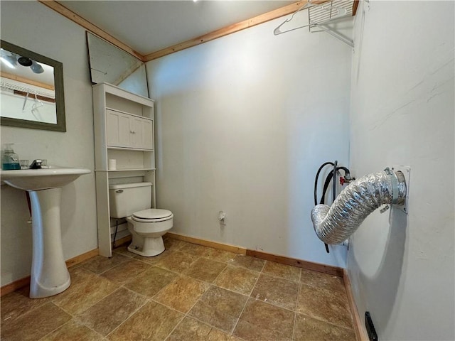 bathroom with stone finish floor, baseboards, and toilet