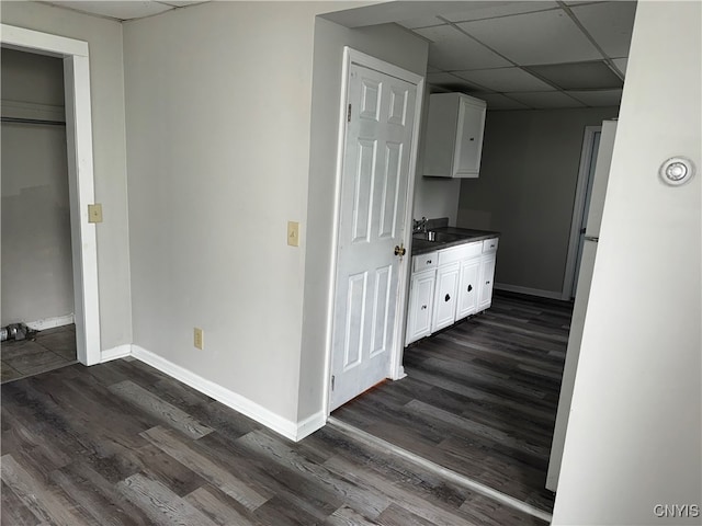 hall featuring dark wood-type flooring, a drop ceiling, and sink