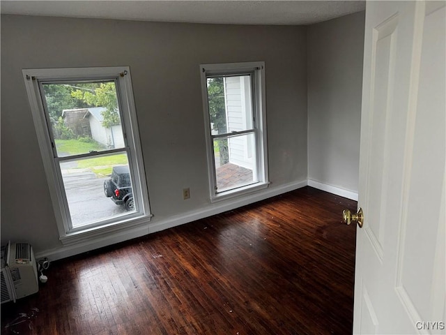 spare room with dark wood-type flooring and baseboards