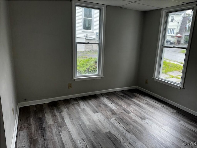 unfurnished room featuring a paneled ceiling, baseboards, and wood finished floors