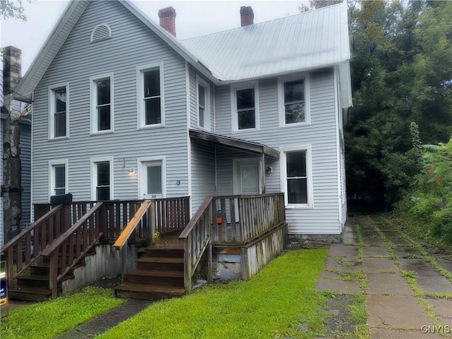 back of house with metal roof and a chimney