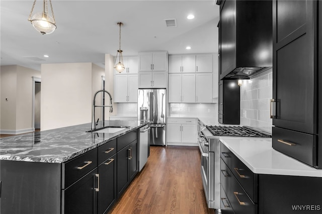 kitchen with sink, wood-type flooring, decorative backsplash, high end appliances, and wall chimney range hood