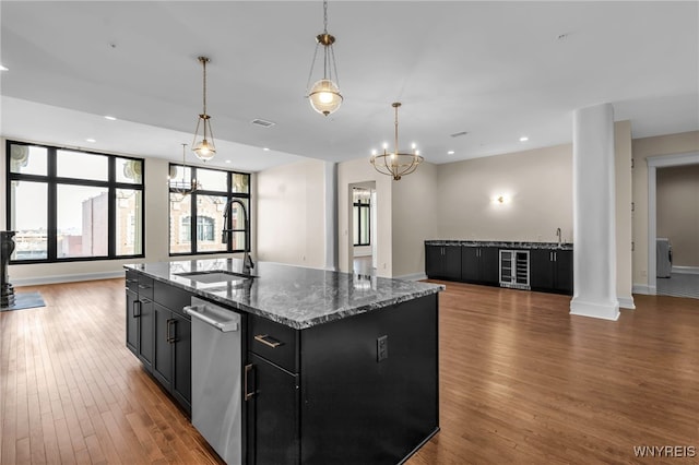 kitchen featuring sink, wood-type flooring, stainless steel dishwasher, stone countertops, and hanging light fixtures