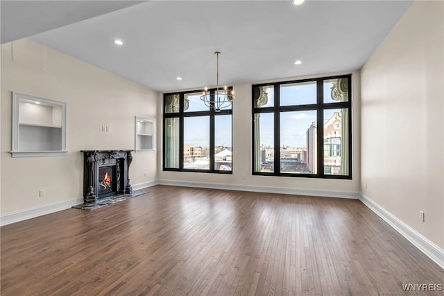 unfurnished living room with hardwood / wood-style floors, a notable chandelier, and a high end fireplace