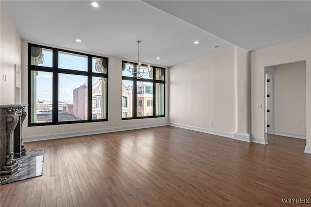 unfurnished living room with a high end fireplace, a notable chandelier, and dark wood-type flooring