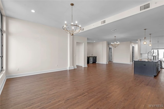 unfurnished living room featuring dark wood-type flooring and an inviting chandelier