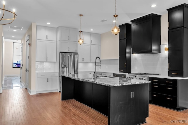 kitchen featuring light hardwood / wood-style flooring, tasteful backsplash, sink, a center island with sink, and stove