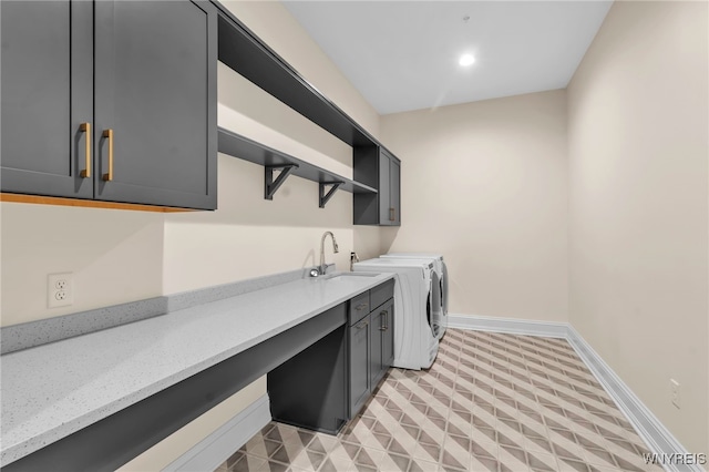 laundry area featuring light tile patterned floors, sink, washer and clothes dryer, and cabinets