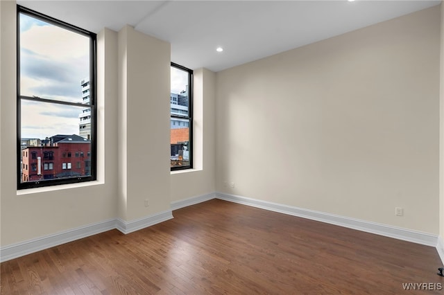 unfurnished room with a wall of windows and wood-type flooring