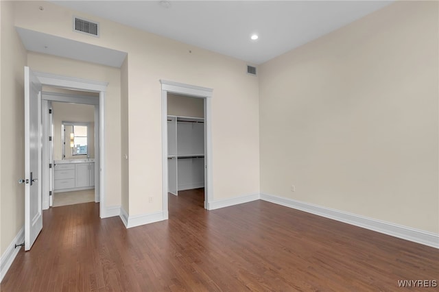 unfurnished bedroom featuring hardwood / wood-style flooring, a closet, and a spacious closet