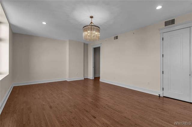 empty room with hardwood / wood-style floors and a notable chandelier