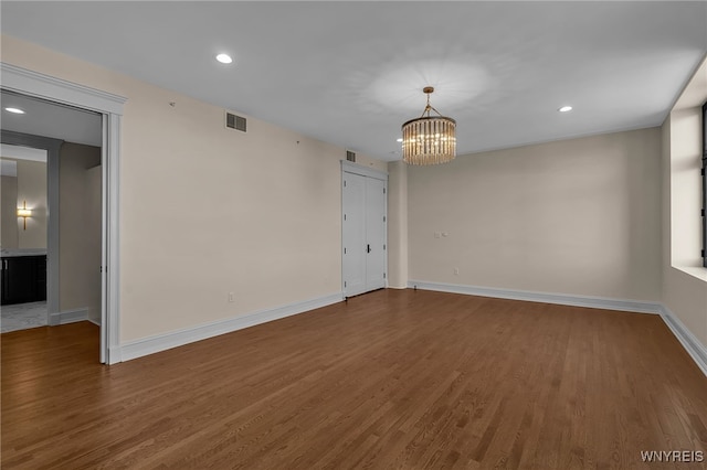 empty room featuring hardwood / wood-style floors and a notable chandelier