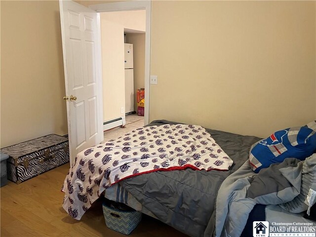 14 E Maple St N, Ellery, NY 14712 - bedroom with freestanding refrigerator, a baseboard heating unit, and light wood-style floors