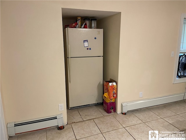 kitchen featuring light tile patterned floors, baseboard heating, and white fridge