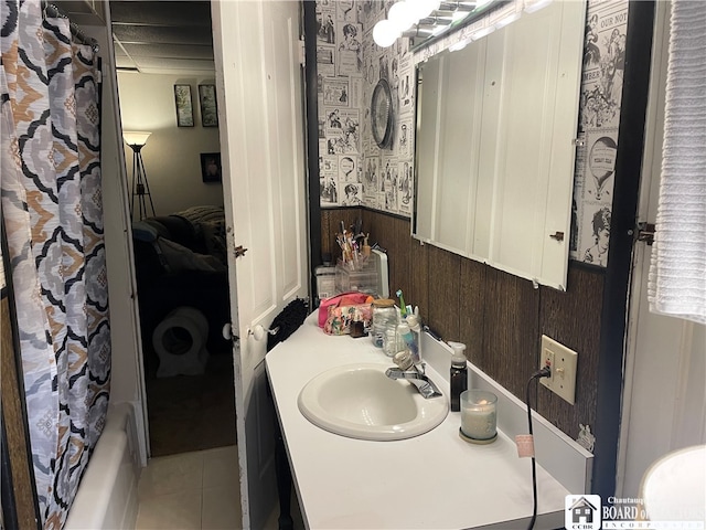 bathroom featuring shower / bathtub combination with curtain, wooden walls, tile patterned flooring, and vanity