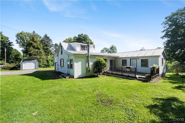 rear view of house featuring a wooden deck, an outdoor structure, a garage, and a yard