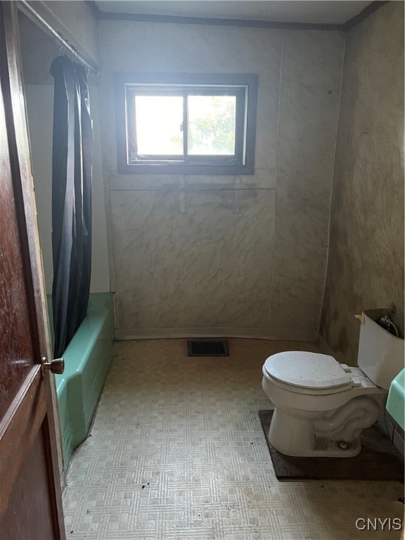 bathroom featuring shower / bath combination with curtain, toilet, and tile patterned flooring