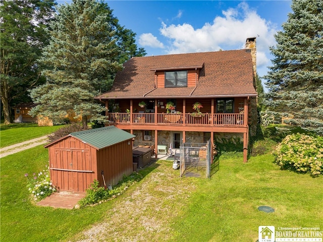 rear view of property featuring a yard, a storage unit, and a deck