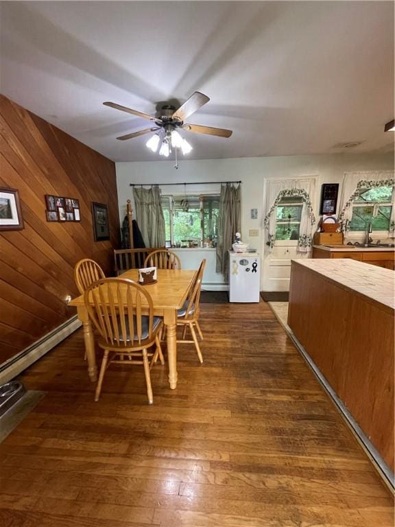 dining area with ceiling fan, sink, dark hardwood / wood-style floors, lofted ceiling, and wood walls