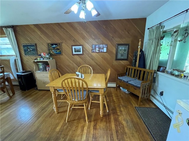 dining space featuring wooden walls, dark hardwood / wood-style floors, and a baseboard heating unit