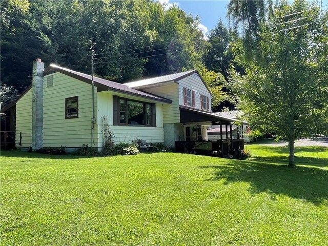 view of side of home featuring a chimney, metal roof, and a yard