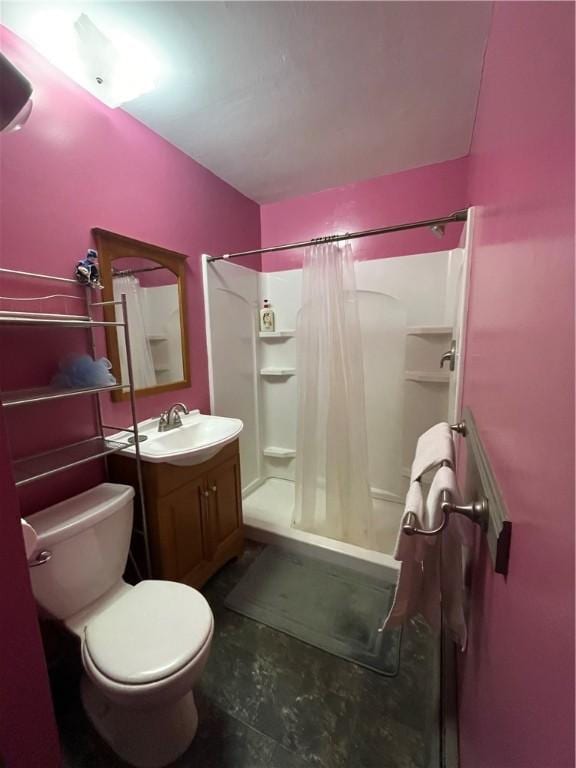 bathroom with toilet, a stall shower, and vanity