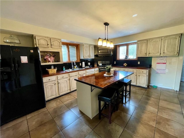 kitchen with sink, a kitchen island, stainless steel appliances, decorative light fixtures, and wooden counters