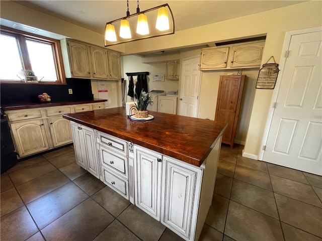 kitchen with a kitchen island, separate washer and dryer, pendant lighting, dark tile patterned flooring, and wooden counters