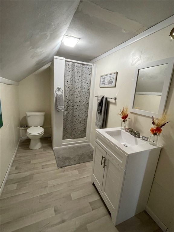 bathroom with vanity, toilet, wood-type flooring, and vaulted ceiling