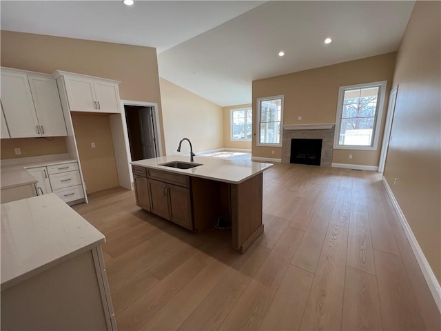 kitchen with a sink, lofted ceiling, light countertops, and light wood finished floors