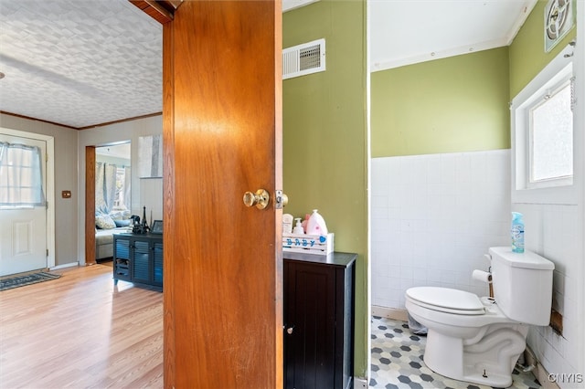 bathroom featuring a textured ceiling, tile walls, toilet, and hardwood / wood-style flooring