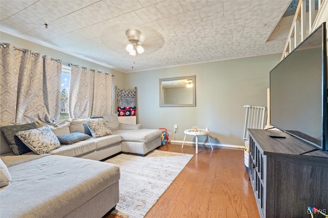 living room featuring hardwood / wood-style flooring, ornamental molding, and ceiling fan