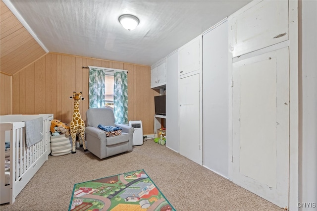 bedroom with vaulted ceiling, light colored carpet, and wooden walls